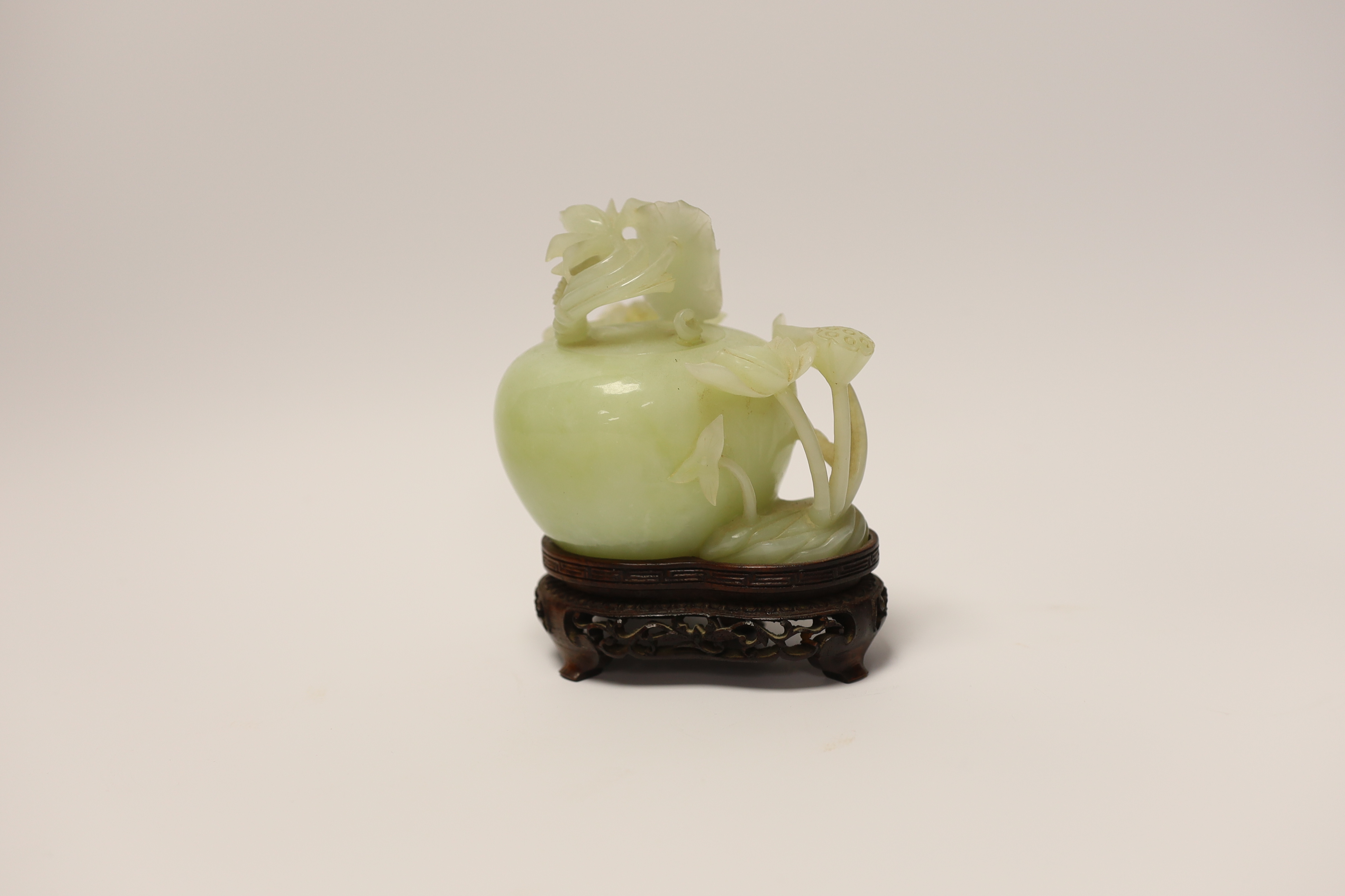 A Chinese carved bowenite jade ‘lotus’ water pot and cover on hardwood stand, 13cm